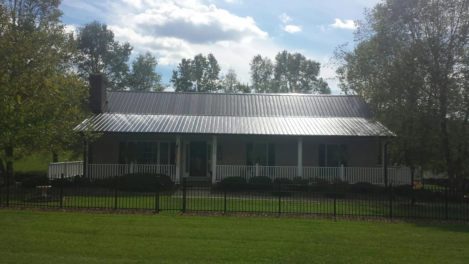 Gray metal roof on a brick ranch with a full width front porch — Gutter Guard Installation work by our crew in Southampton