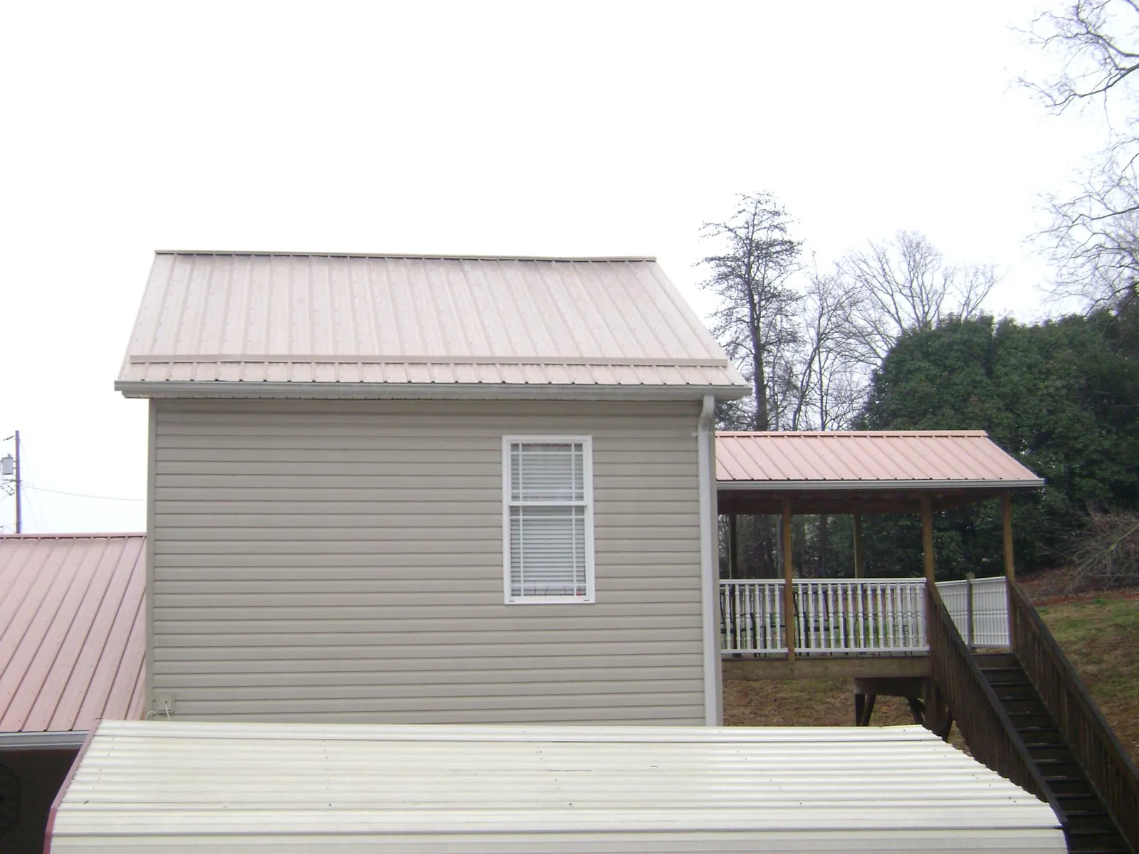 Tan metal roofs on a two story addition and attached porch, from a Roof Replacement job in Southampton