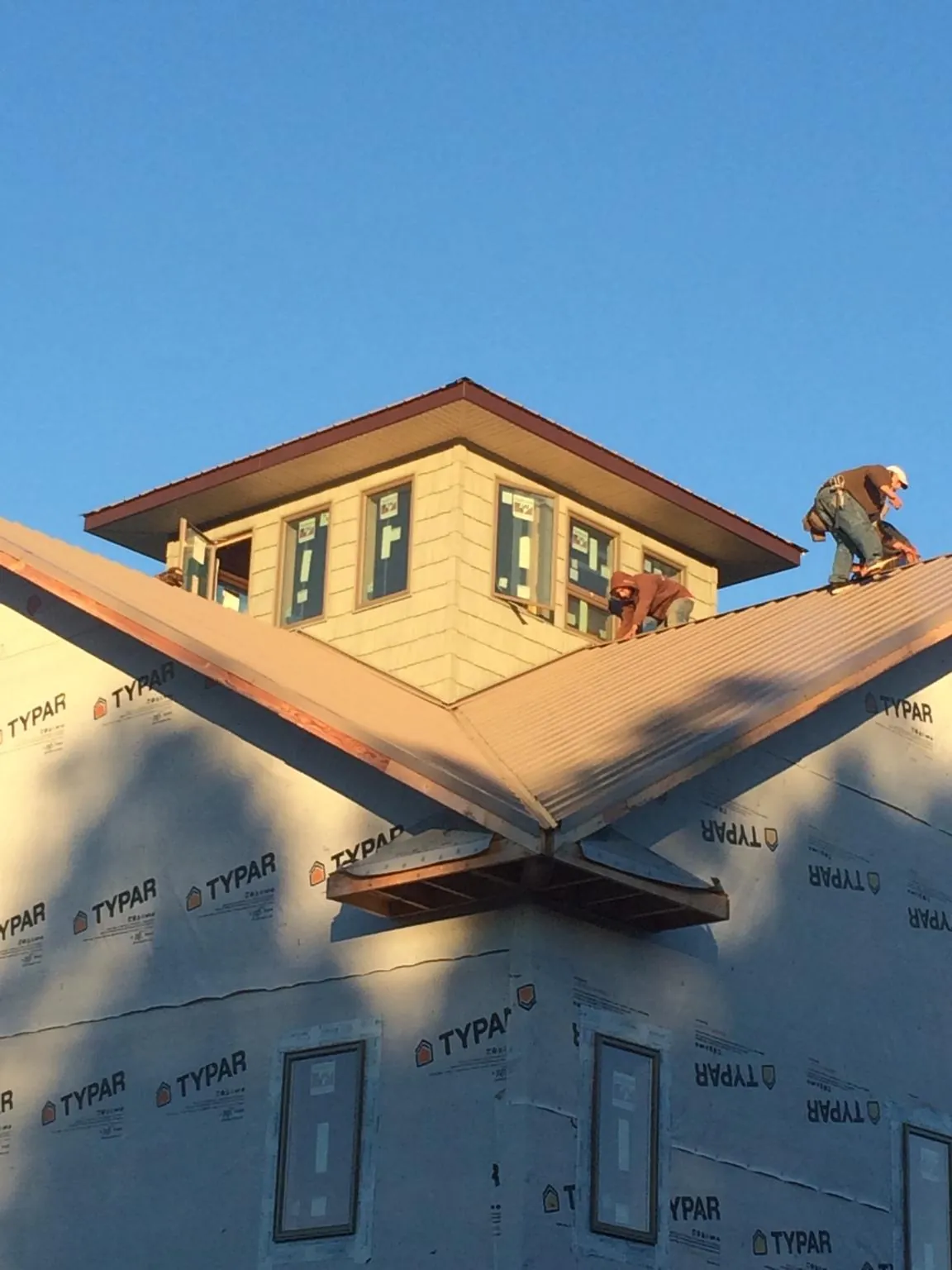 Roofers working around a rooftop cupola on a new metal roof at sunset — Roof Waterproofing in Southampton by Roofing Brothers
